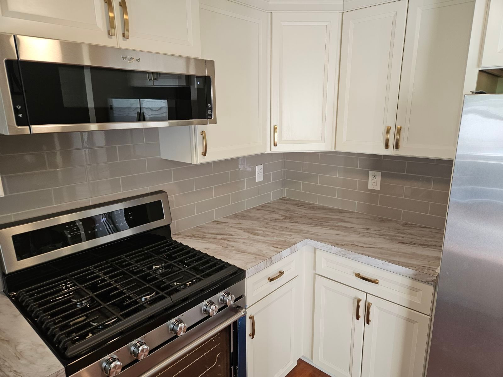 A kitchen with a stove , microwave , refrigerator and white cabinets.