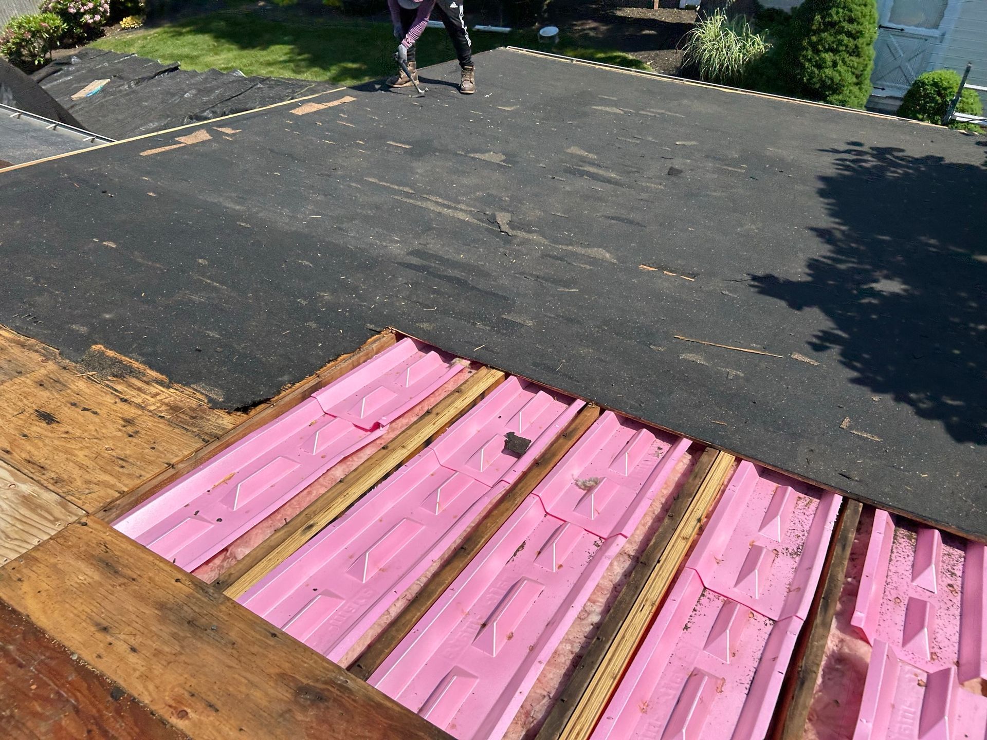A person is standing on a roof with a pink roof covering.