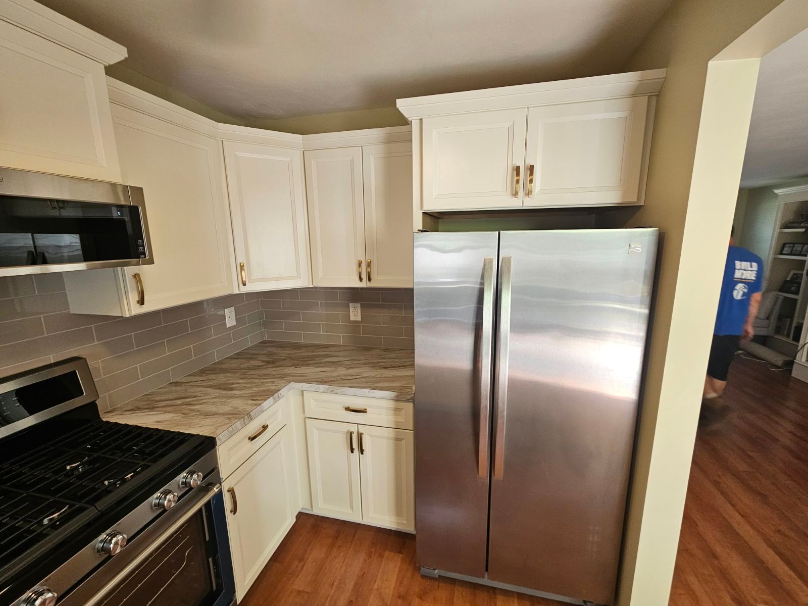 A kitchen with white cabinets and a stainless steel refrigerator