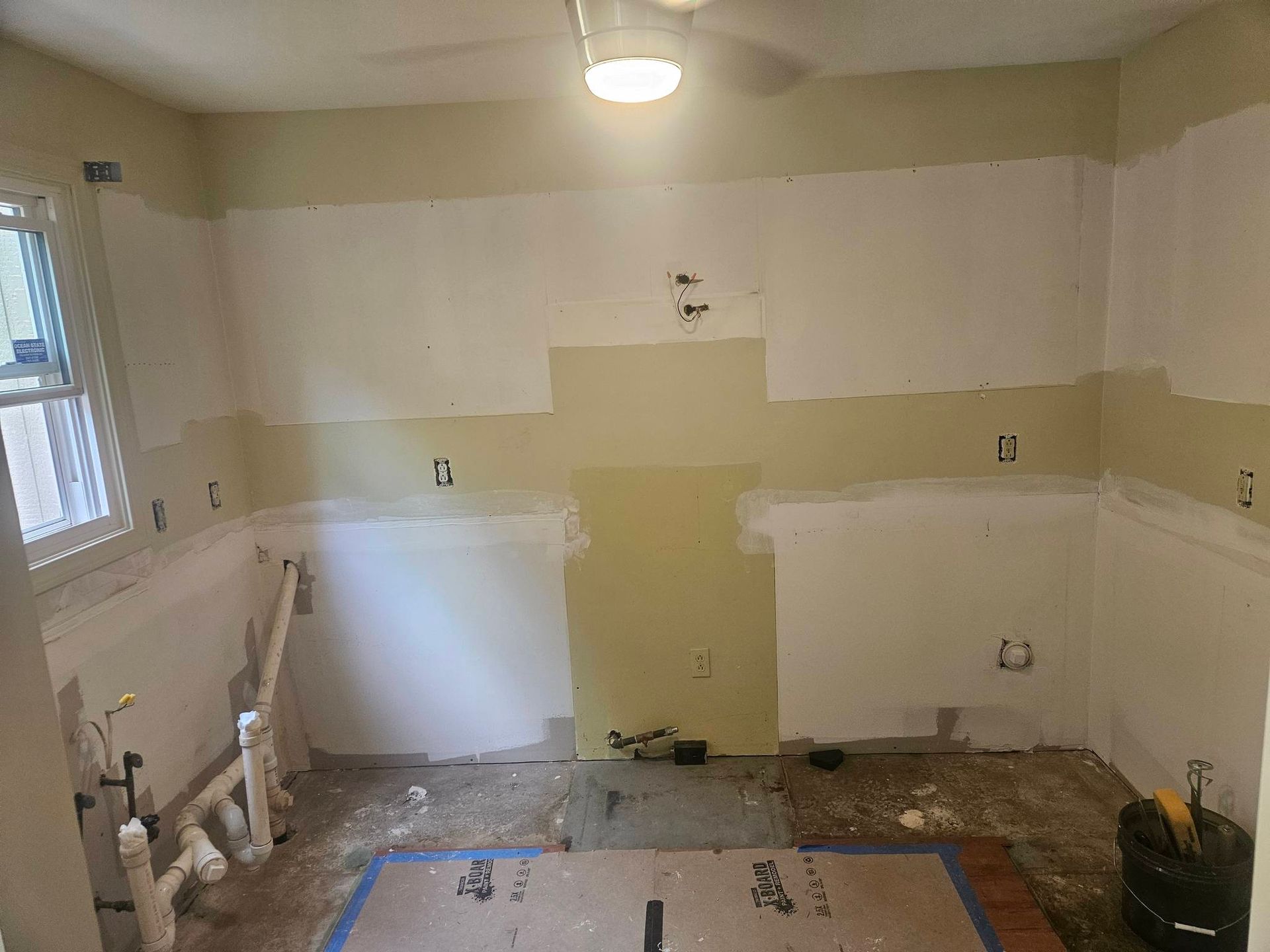 A kitchen that is being remodeled with a ceiling fan.