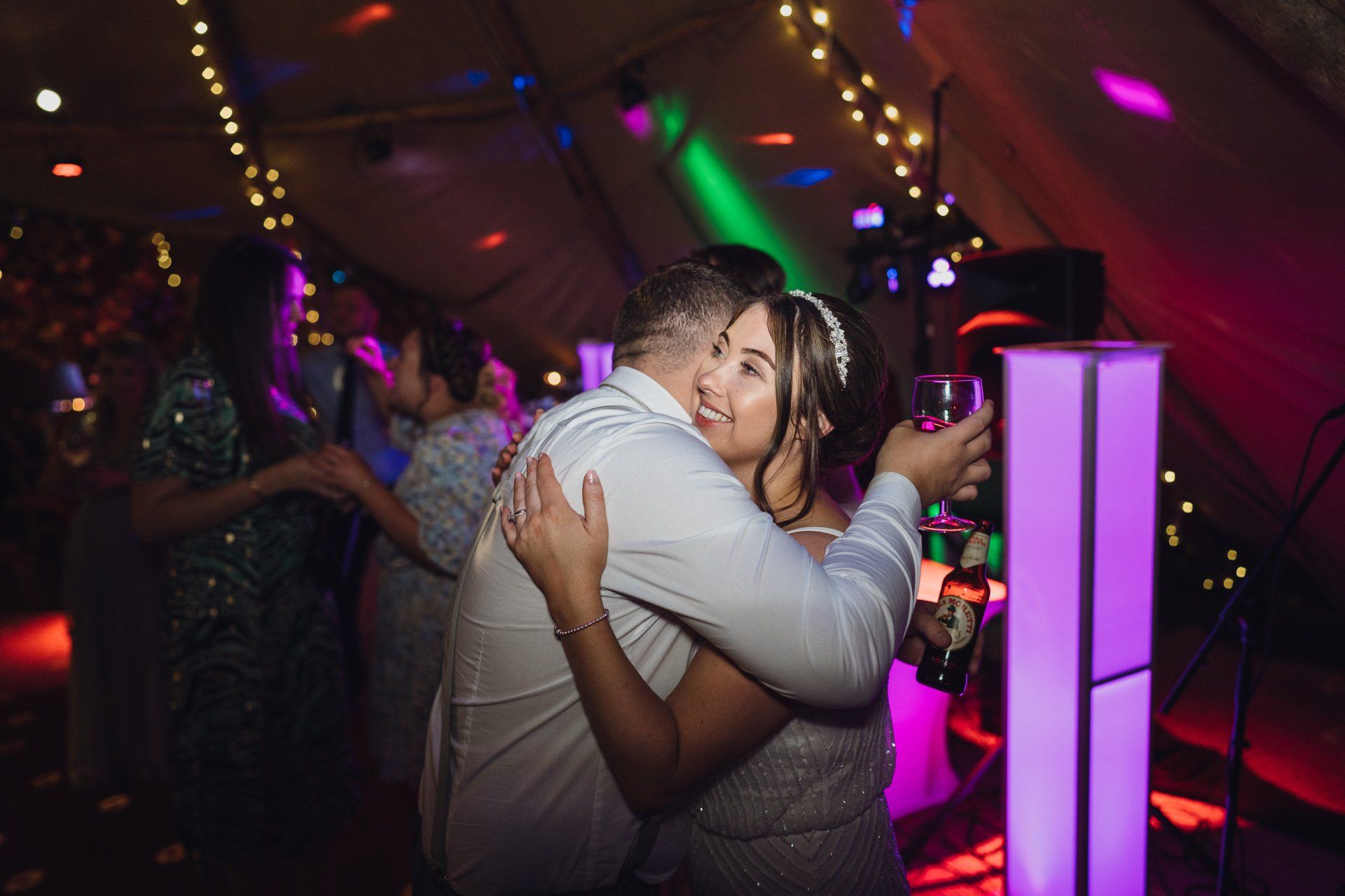 SpectrumDJ's lights in the background as the bride is congratulated by a guest