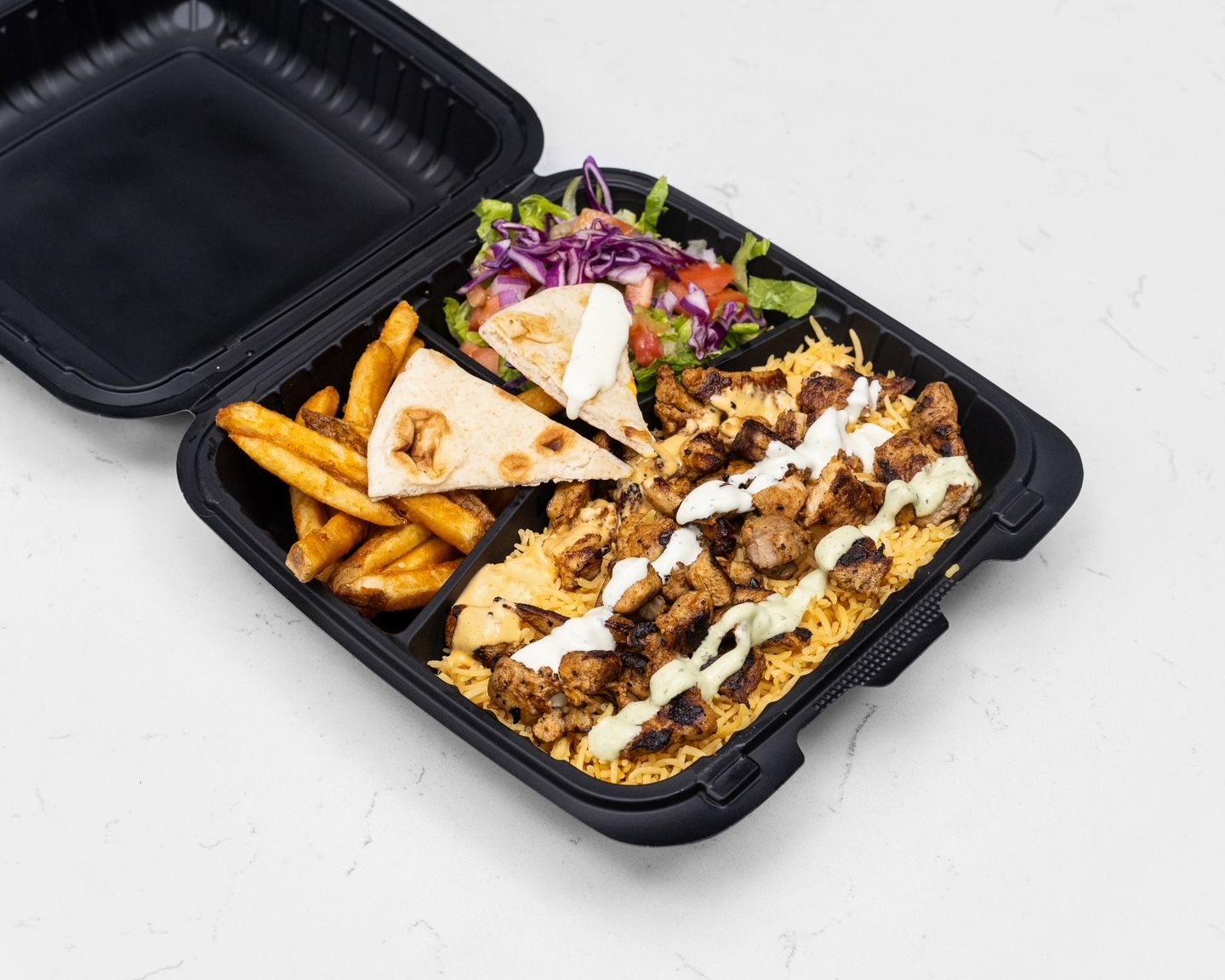 Chicken and rice platter with fries, salad, and pita bread in a black takeout container.