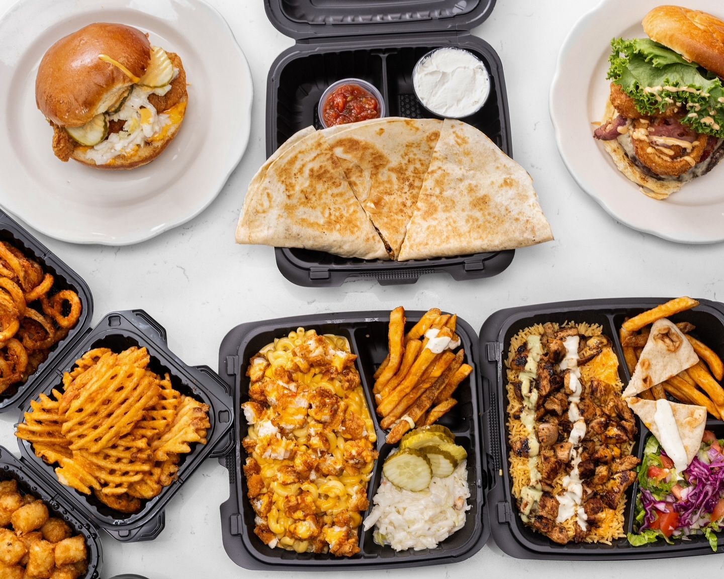 Assortment of takeout meals: sandwiches, quesadilla, fries, and bowls.