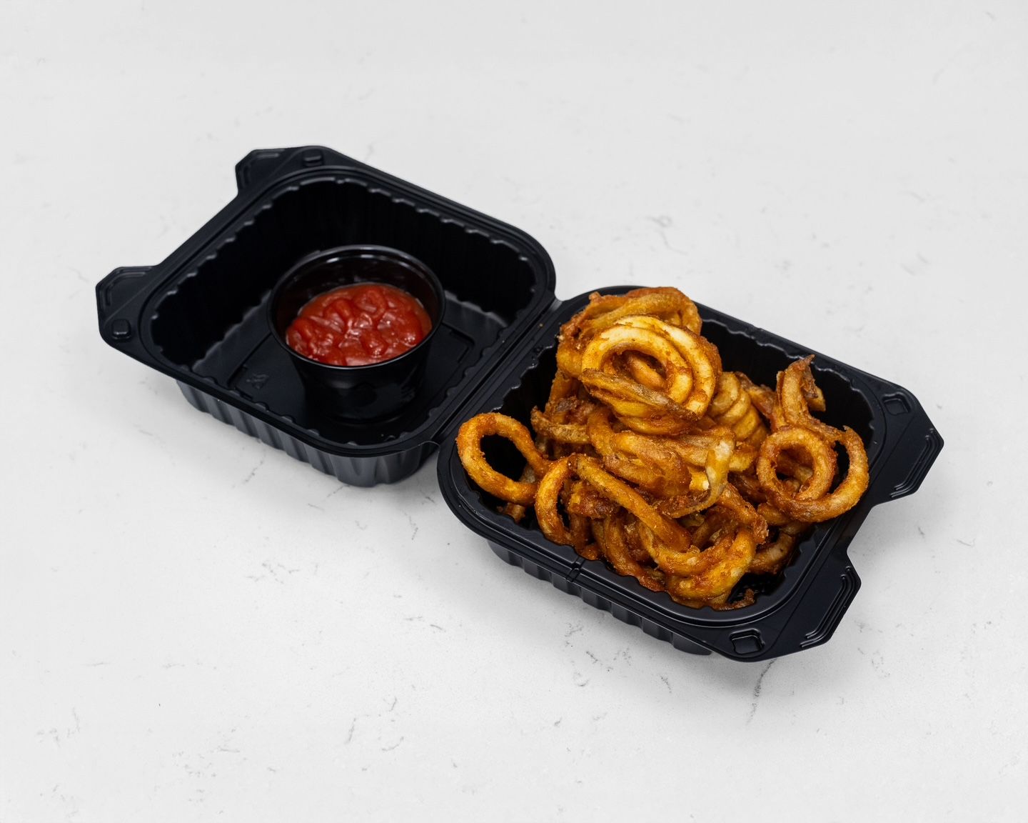 Curly fries and ketchup in black containers.