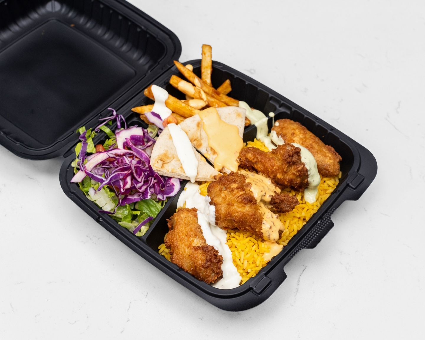 Chicken and rice platter with fries, salad, and pita bread in a black takeout container.