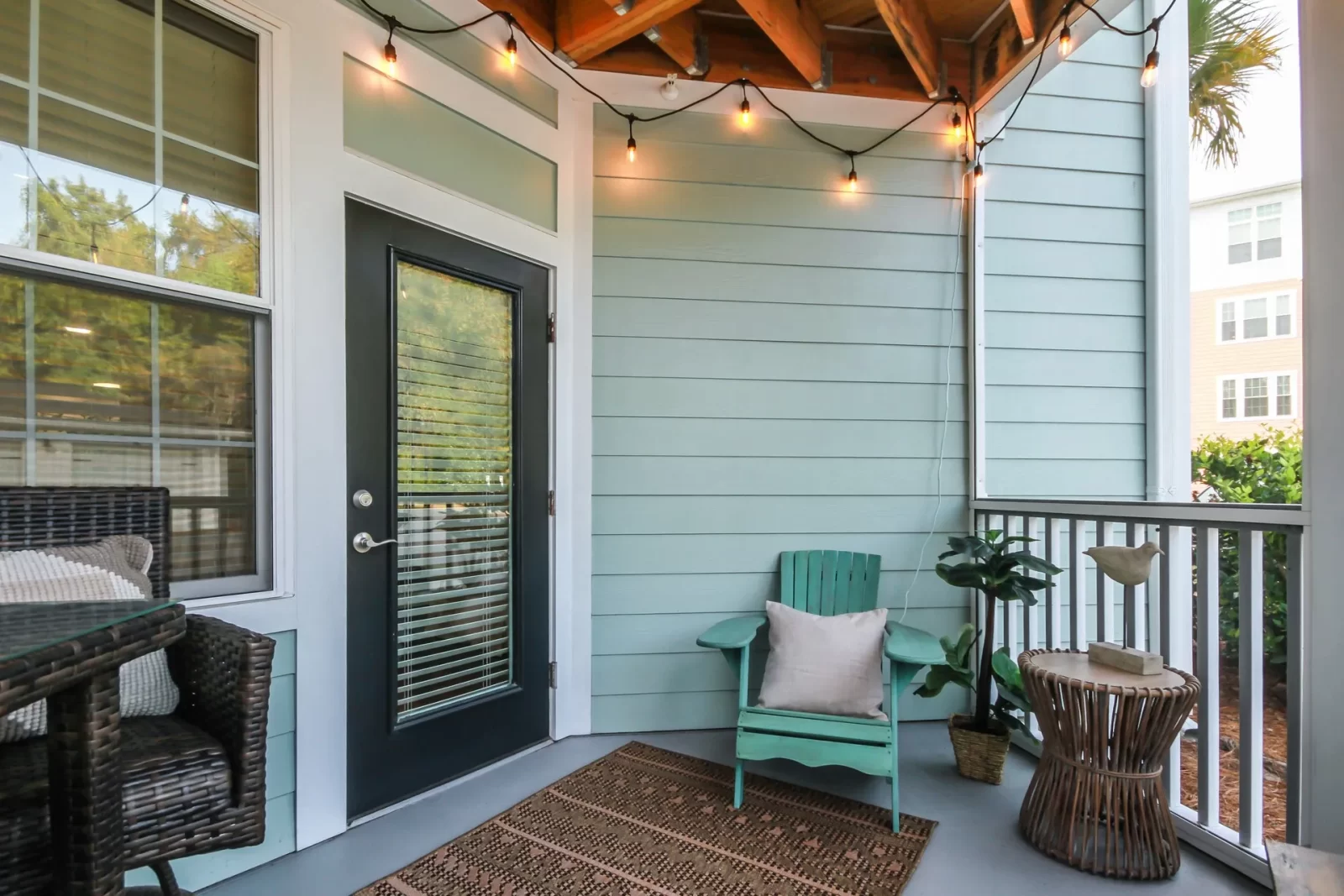 A balcony with a green chair and a table with lights hanging from the ceiling.