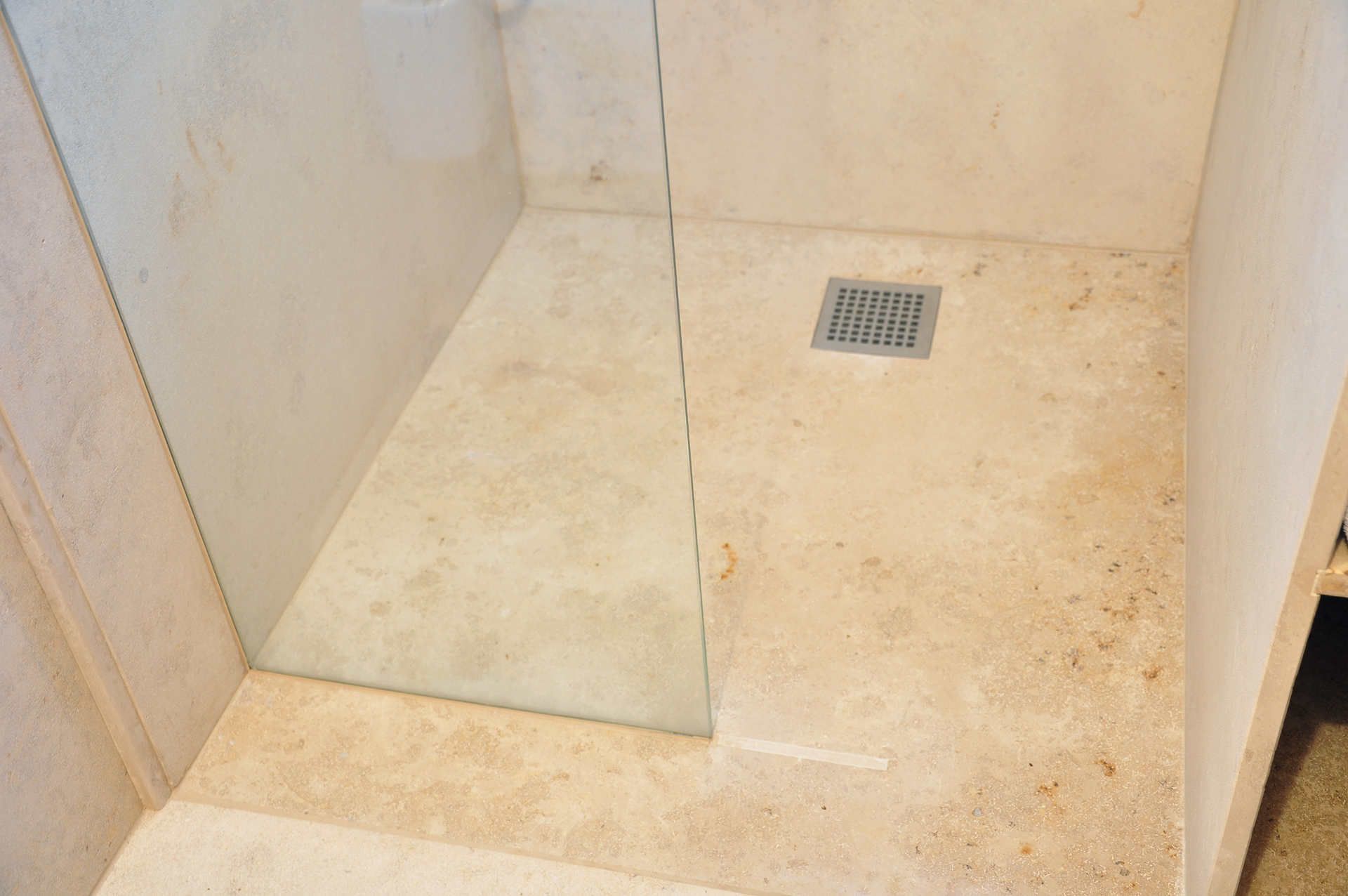 Ein Badezimmer mit ebenerdiger Dusche und Abfluss im Boden.