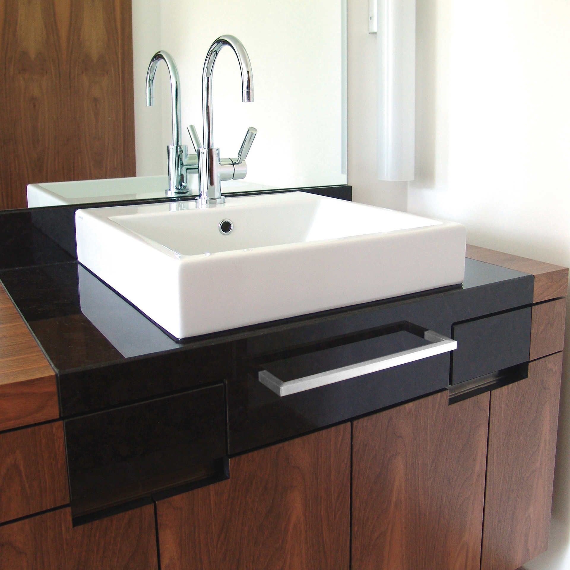 Ein Waschbecken mit zwei Wasserhähnen und einem Spiegel