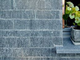 Eine Topfpflanze steht auf einem Fensterbrett neben einer Backsteinmauer.