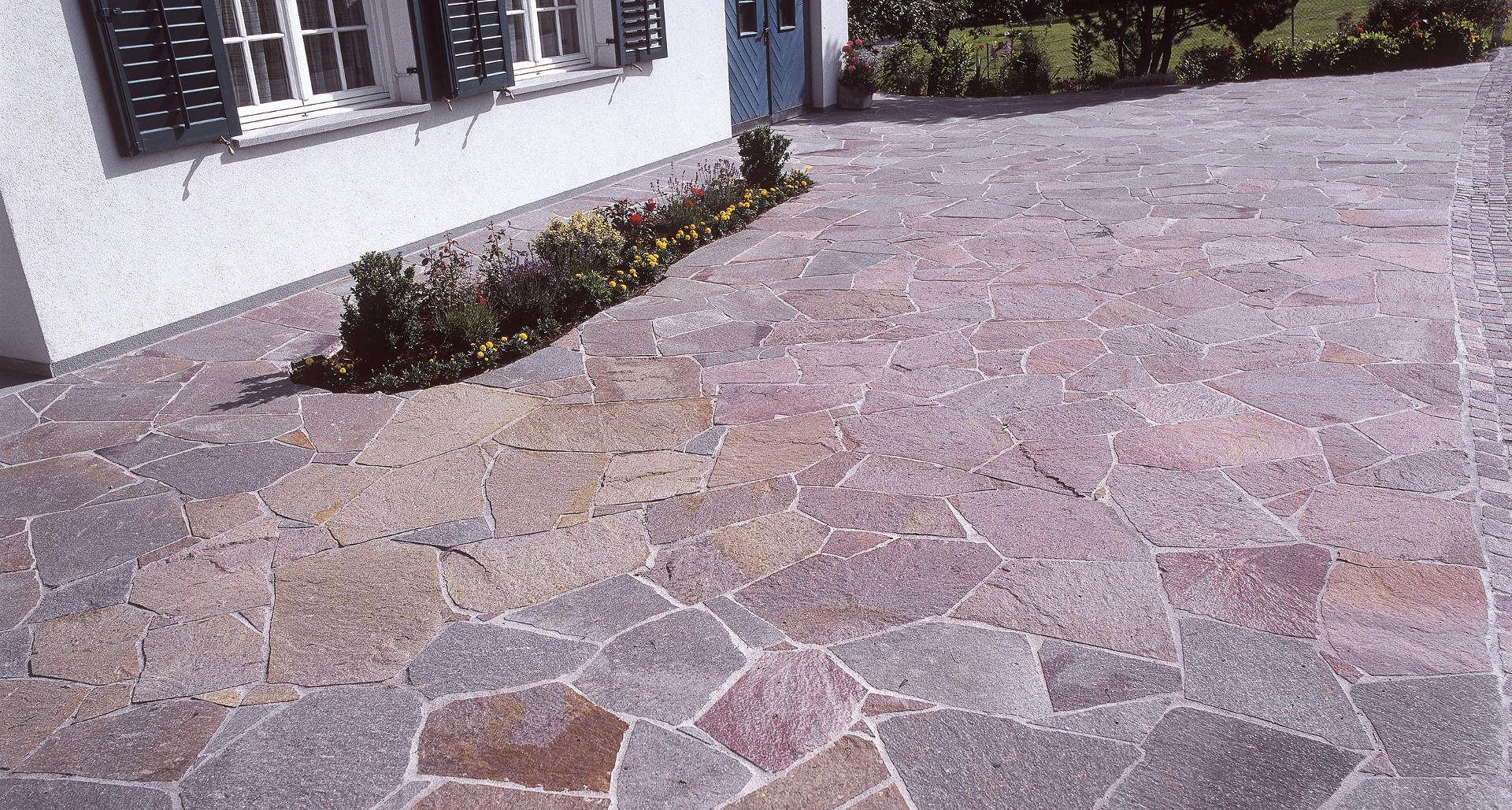 Eine Steinauffahrt mit einem weißen Haus im Hintergrund