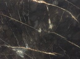 Eine Nahaufnahme einer Arbeitsplatte aus schwarzem Marmor mit goldenen Adern.