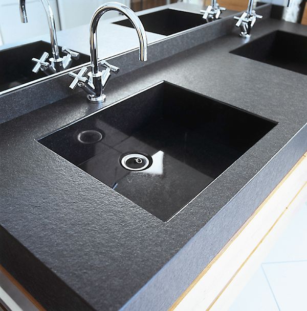 Eine schwarze Arbeitsplatte mit zwei Waschbecken und einem Spiegel