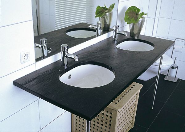 Ein Badezimmer mit zwei Waschbecken und einem Wäschekorb