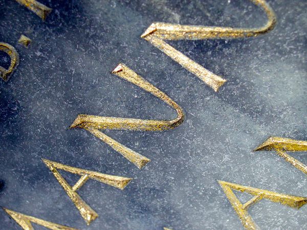 Eine Nahaufnahme eines Zifferblatts mit goldenen Buchstaben auf blauem Hintergrund.