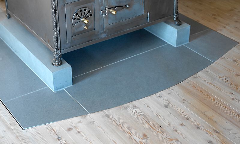 Auf einem Holzboden steht ein Holzofen.