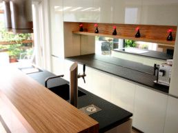 Eine Küche mit weißen Schränken, schwarzen Arbeitsplatten und einer Holzarbeitsplatte.