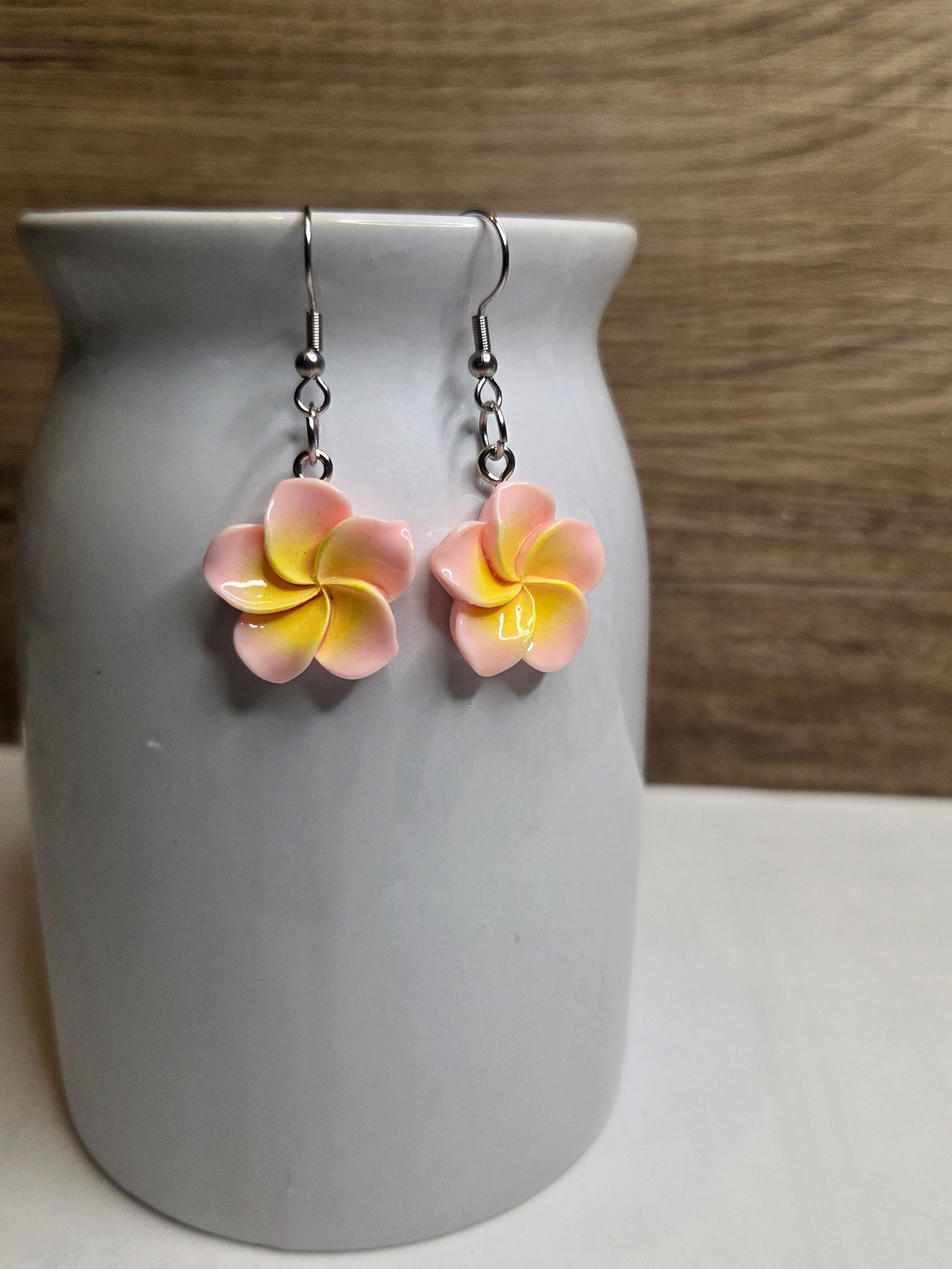 Roze en gele bloemoorbellen hangen aan een grijze vaas.