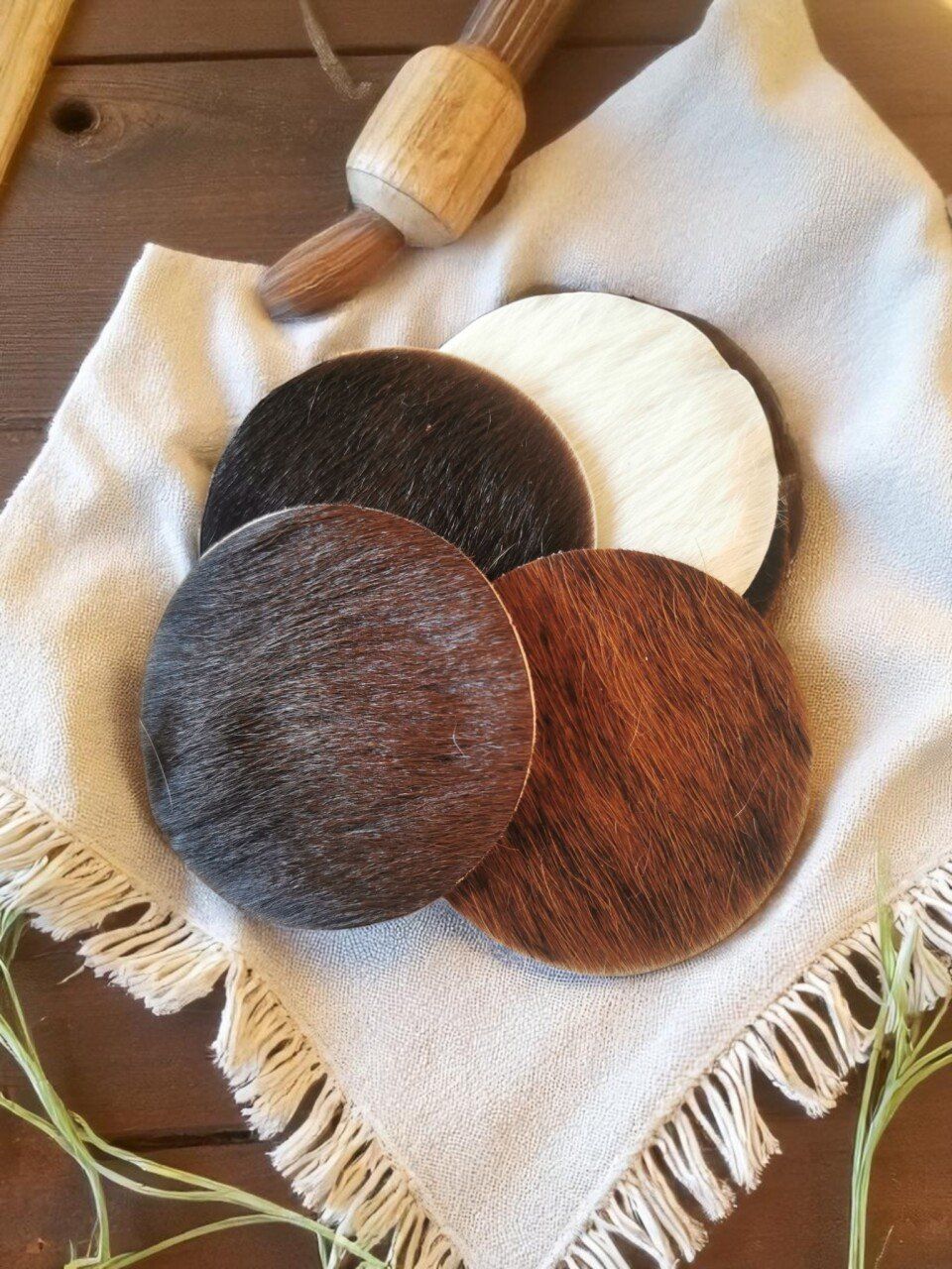 Onderzetters in verschillende kleuren op een wit linnen tafelkleed, met een houten deegroller op de achtergrond.