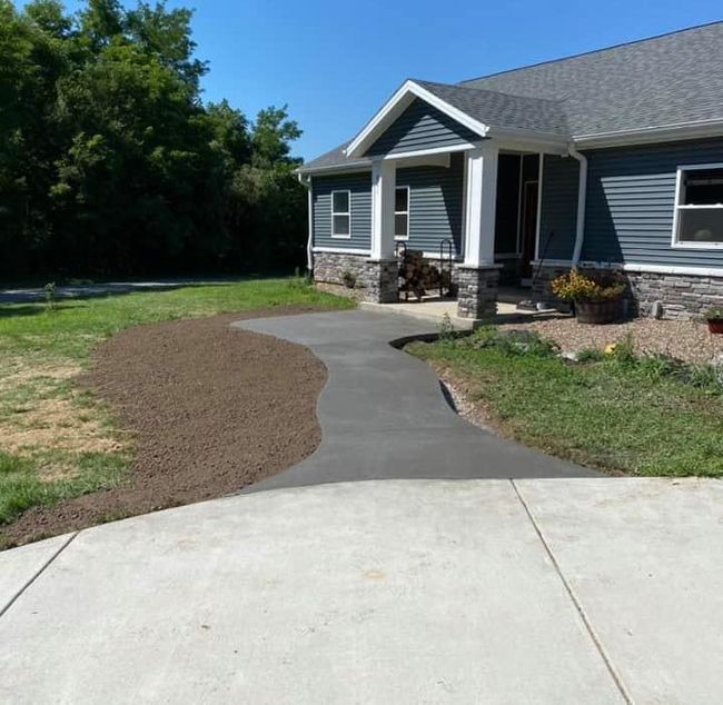 A concrete walkway curves toward a blue-sided house with a porch and gray roof.