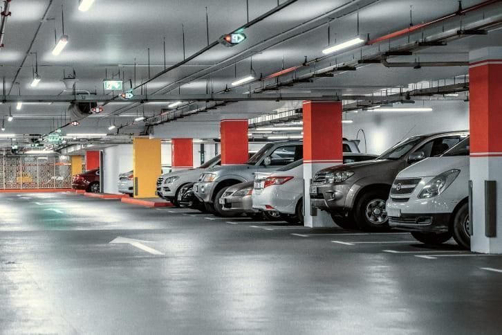 Cars parked in a multi-level parking garage with red and yellow support pillars.