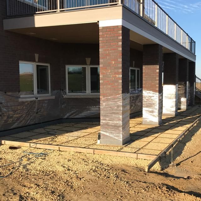 Under-deck patio under construction with brick pillars and gravel base.
