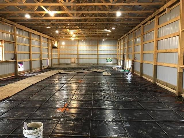 Interior of a large unfinished building with wooden beams, metal siding, and a wire mesh floor.