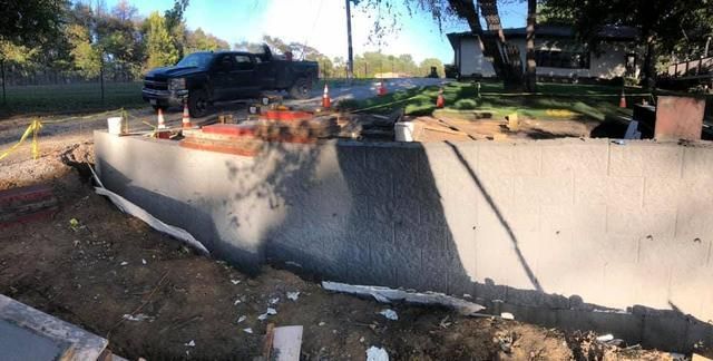 Construction site with a concrete wall, a black pickup truck, and orange traffic cones.