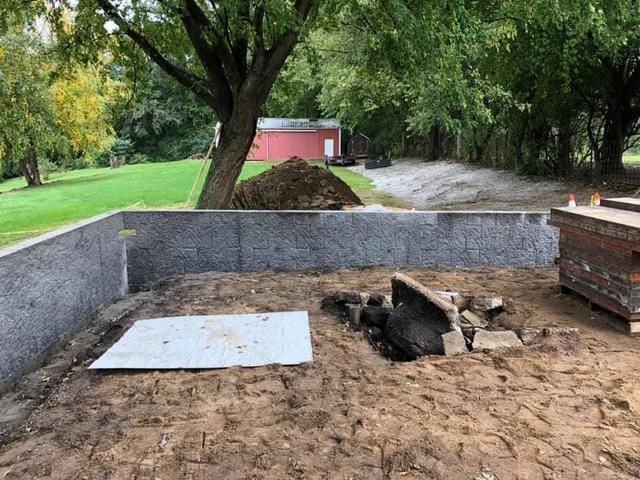 Concrete foundation with dirt interior. A small pile of dirt sits in the distance, with trees surrounding the open area.