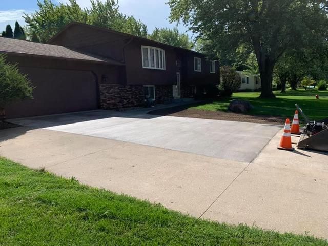 Brown house with new concrete driveway and safety cones.