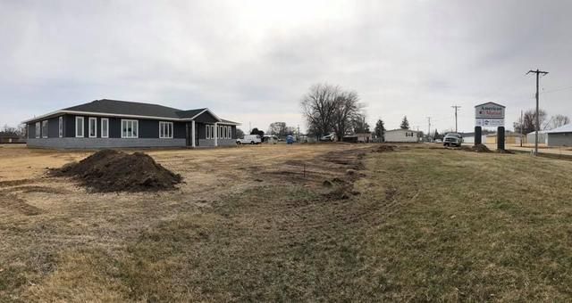 A newly built one-story house on a grassy field; construction or landscaping in progress. Overcast sky.