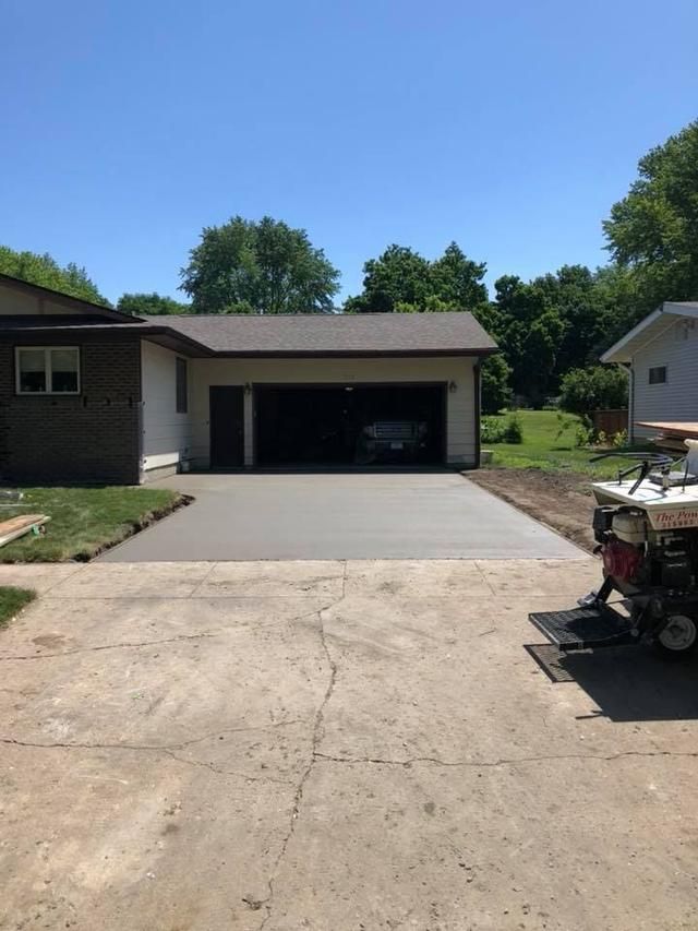 New concrete driveway leading to a garage; sunny day.