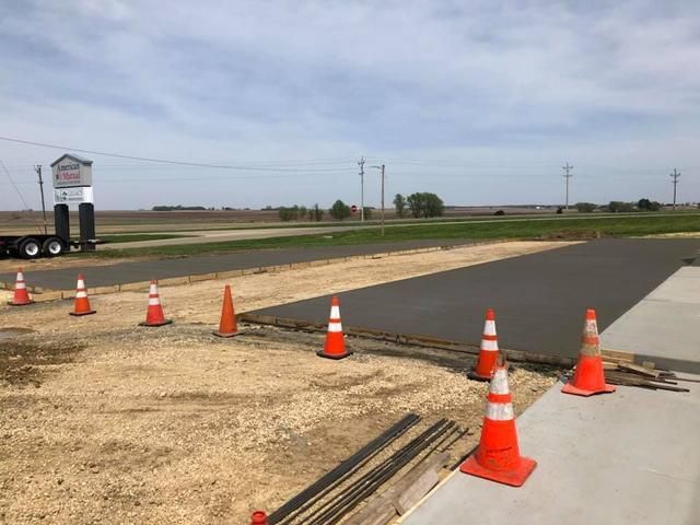 Freshly poured concrete area under construction, with safety cones and gravel.