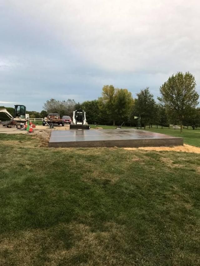 Concrete slab on grass with construction equipment in the background. Overcast day.