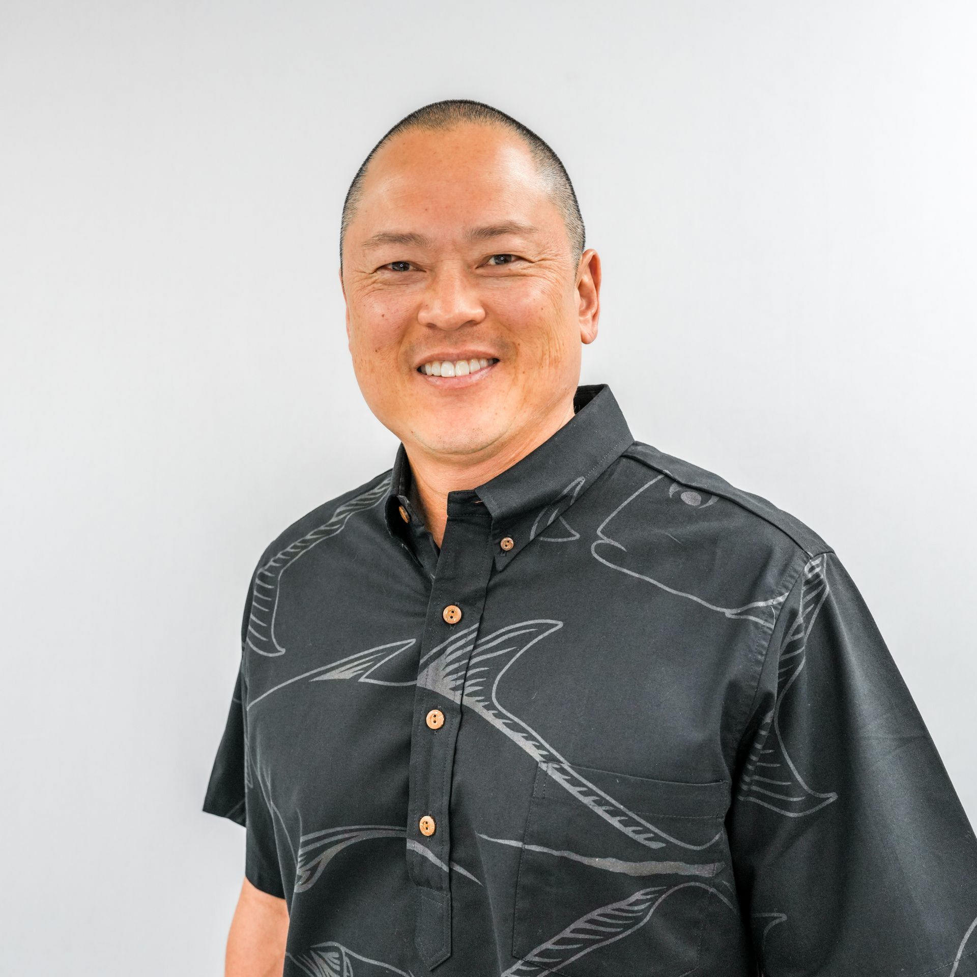 A woman with long dark hair is smiling and wearing a black shirt.