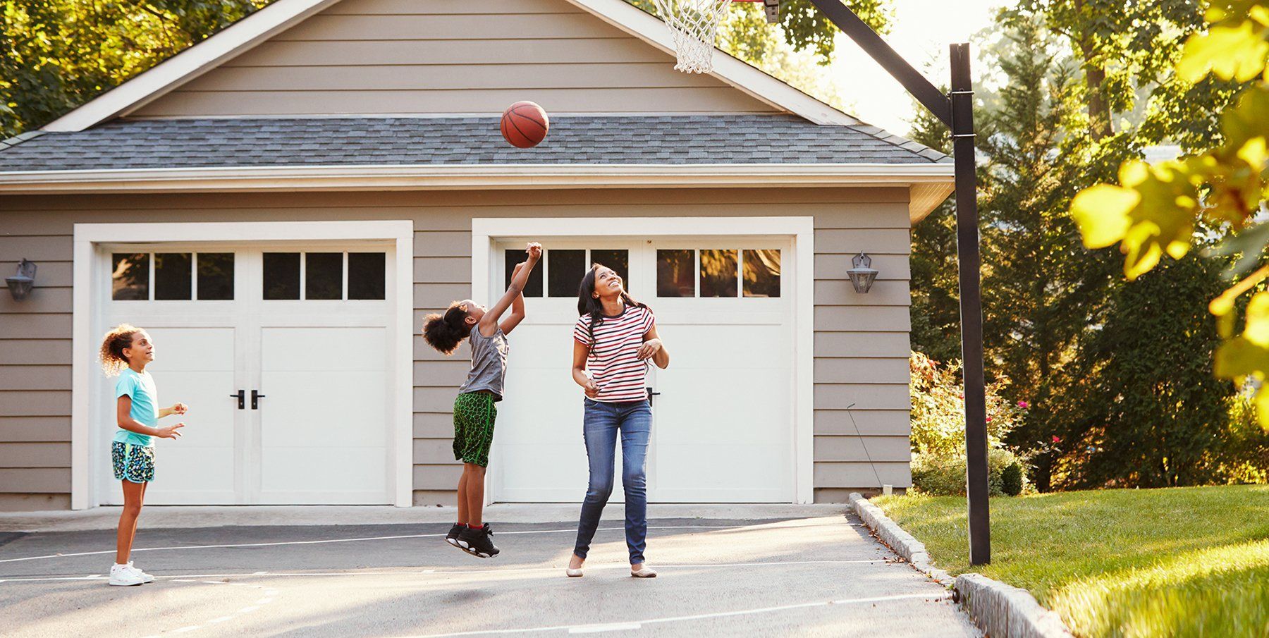 Family playing basketball after buying a new garage door.