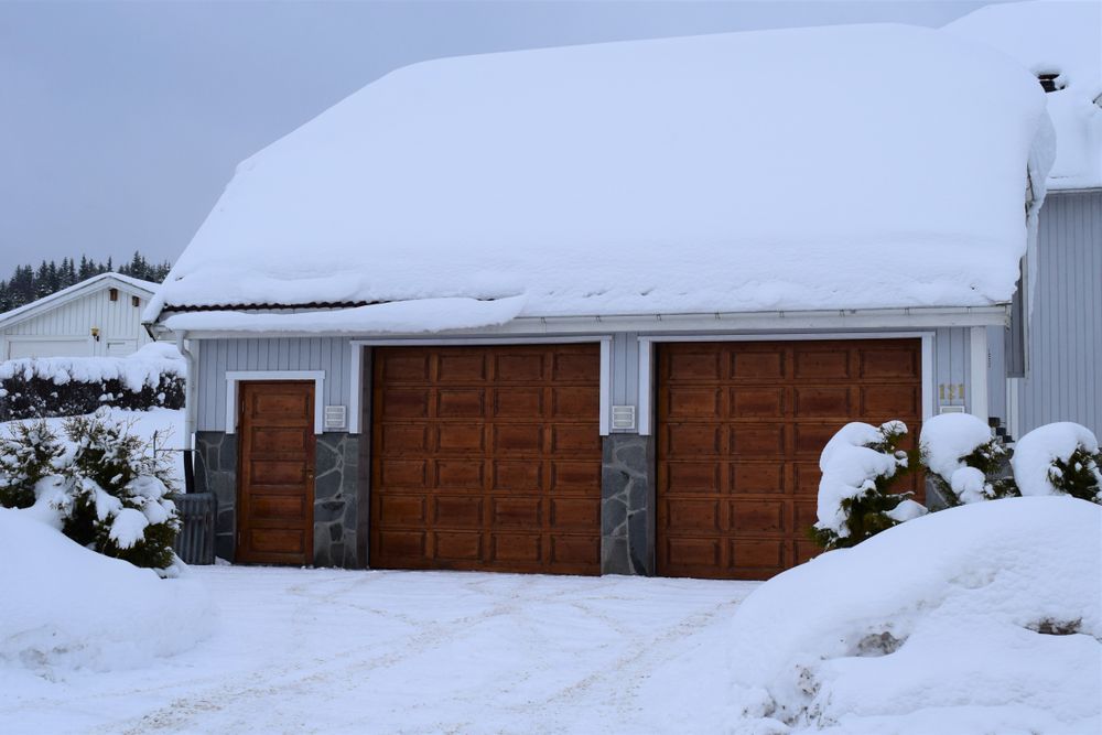 Snow-covered two-car garage with frozen shut brown garage doors