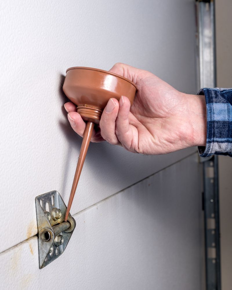 A person is holding a funnel attached to a garage door