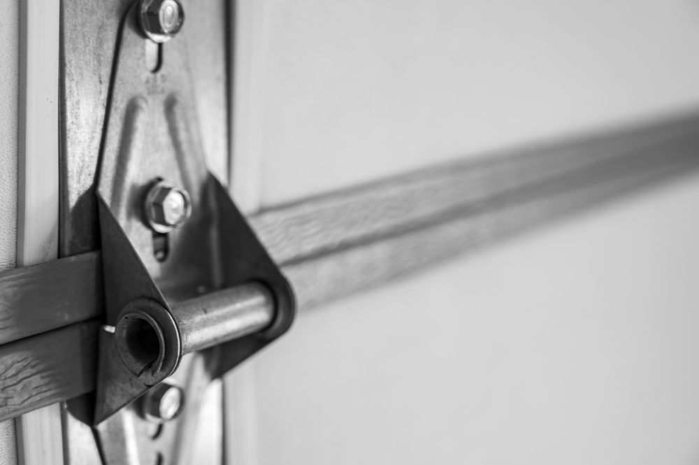 A black and white photo of a garage door hinge.