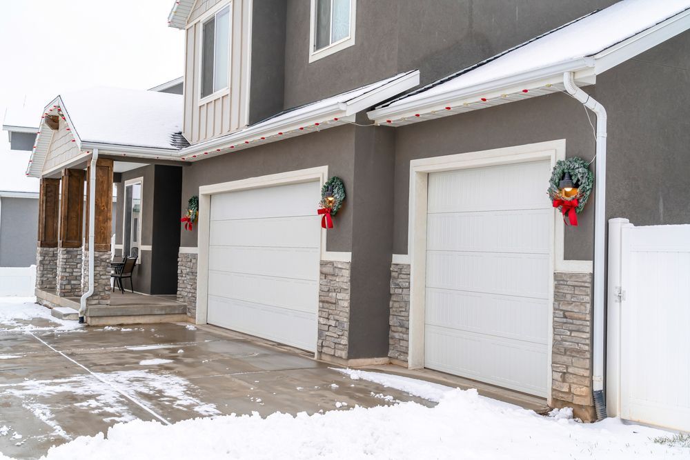 A closed garage door in the winter with snow on the ground.