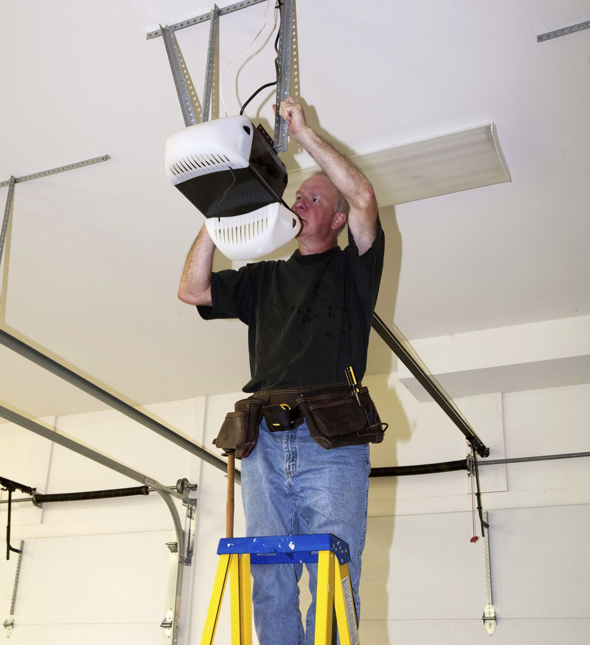man on a ladder showing how to reset garage door opener