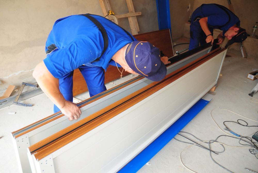 Two men are working on a piece of wood in a room.