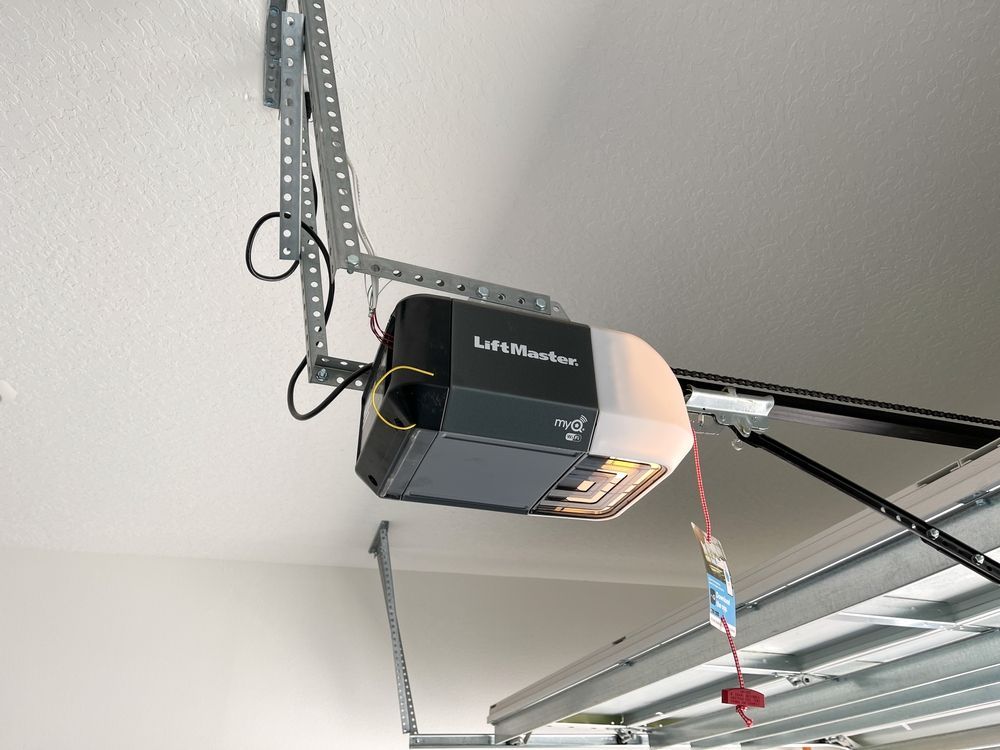 A garage door opener is hanging from the ceiling of a garage.