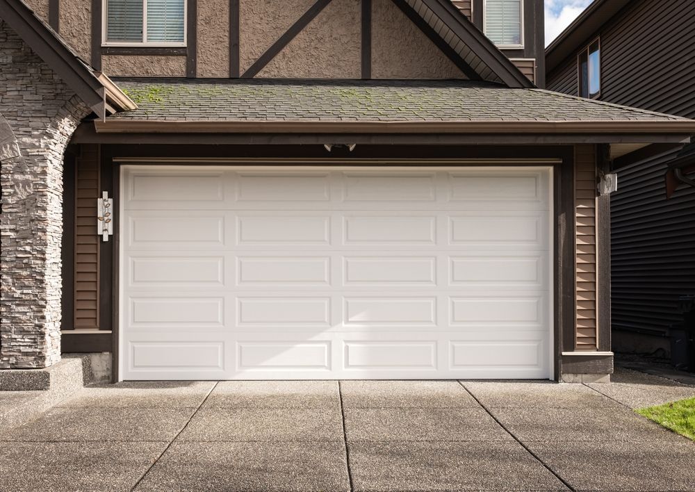 a white sectional garage door is sitting in front of a house.