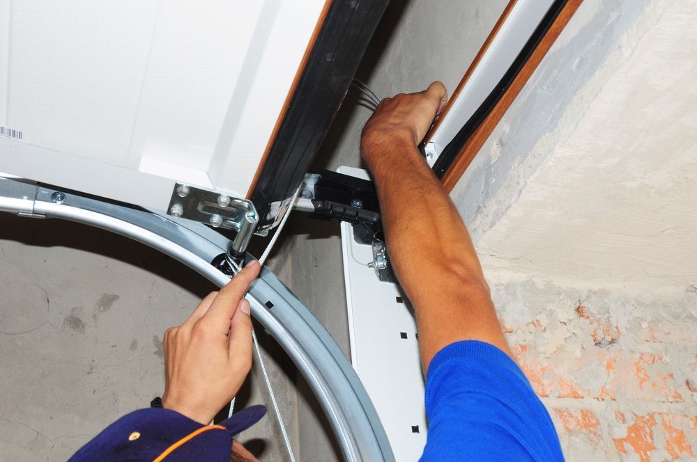 A man is fixing a garage door with a screwdriver.