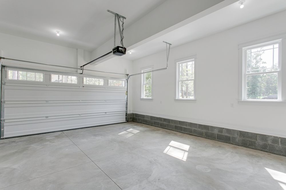 An empty garage with a garage door open and a ceiling fan.