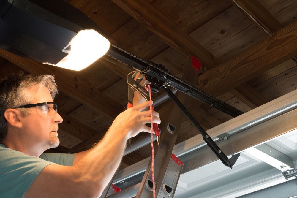 A man is working on a garage door opener in a garage.