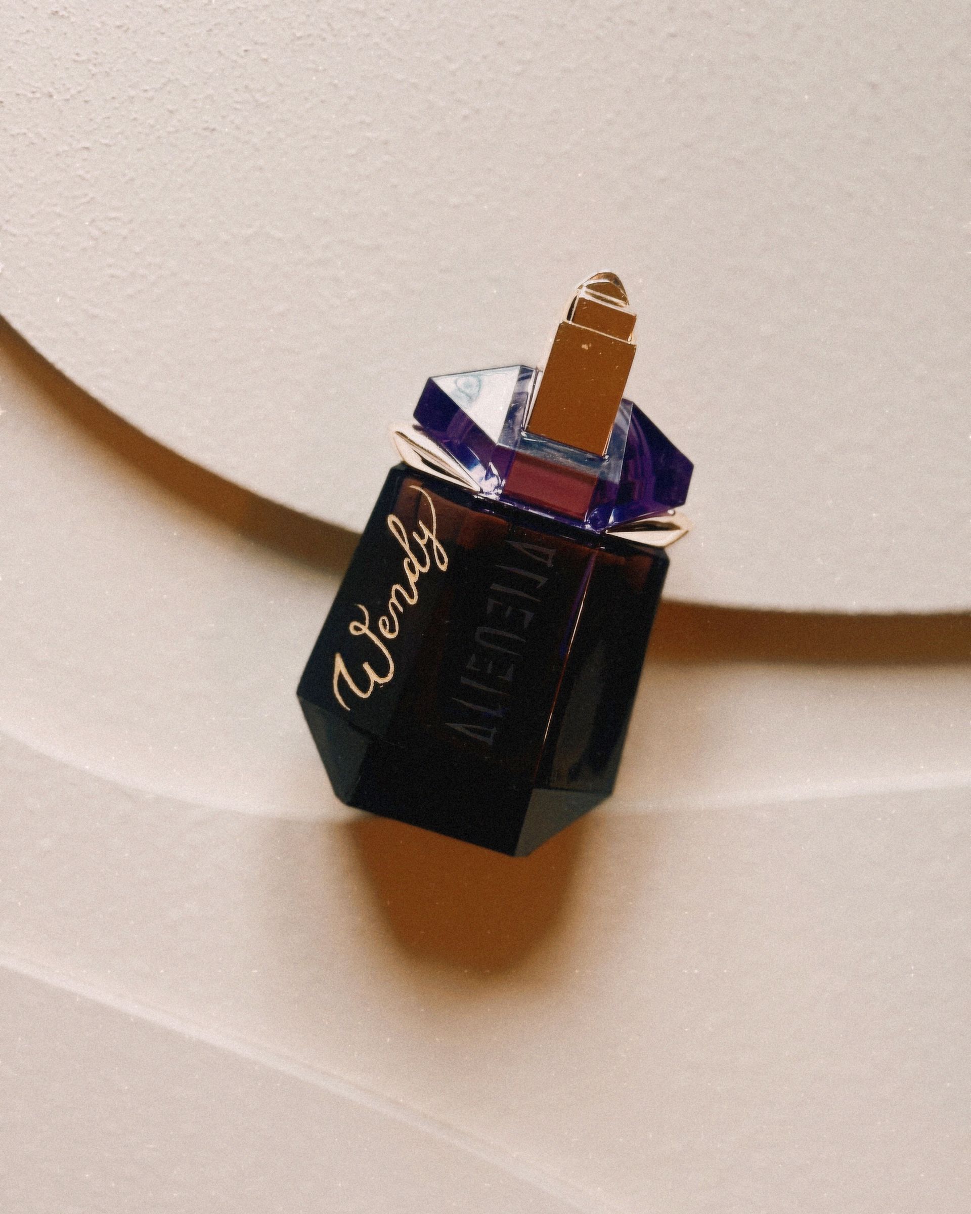 Een flesje Alien Mugler parfum staat op een wit oppervlak