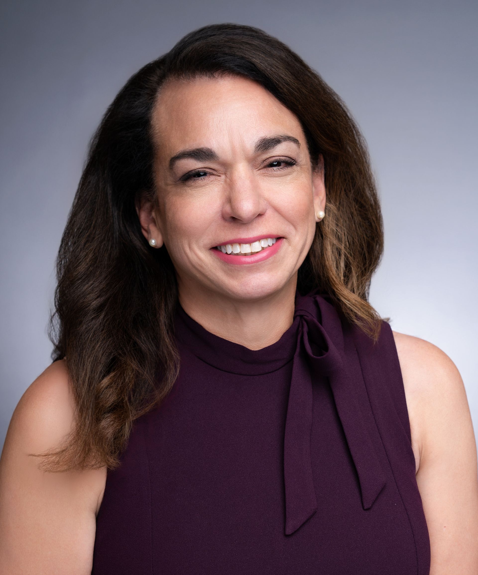 A woman in a purple dress is smiling for the camera.
