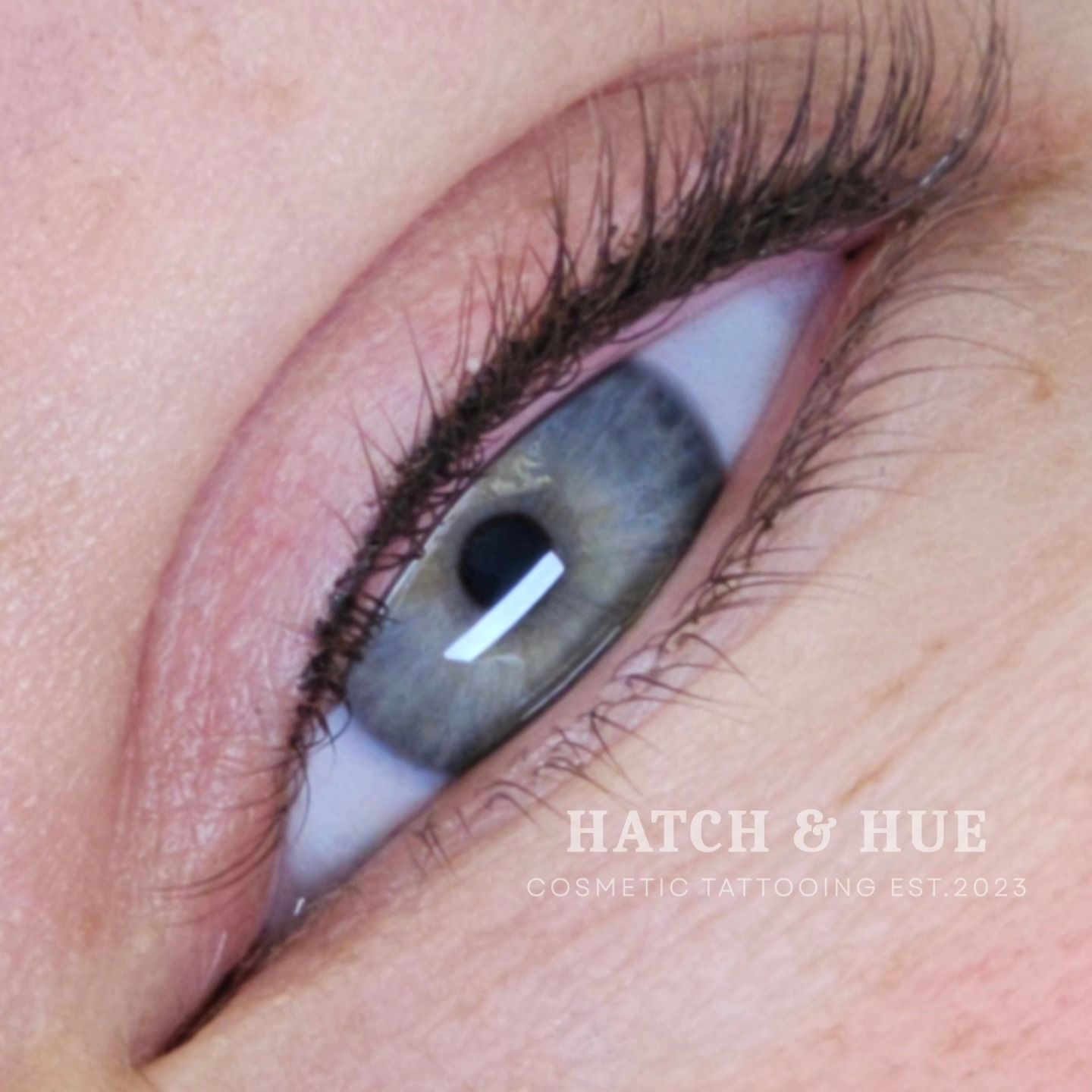 Close-up of a blue eye with eyeliner. The skin is light-toned, and the eye is in focus.