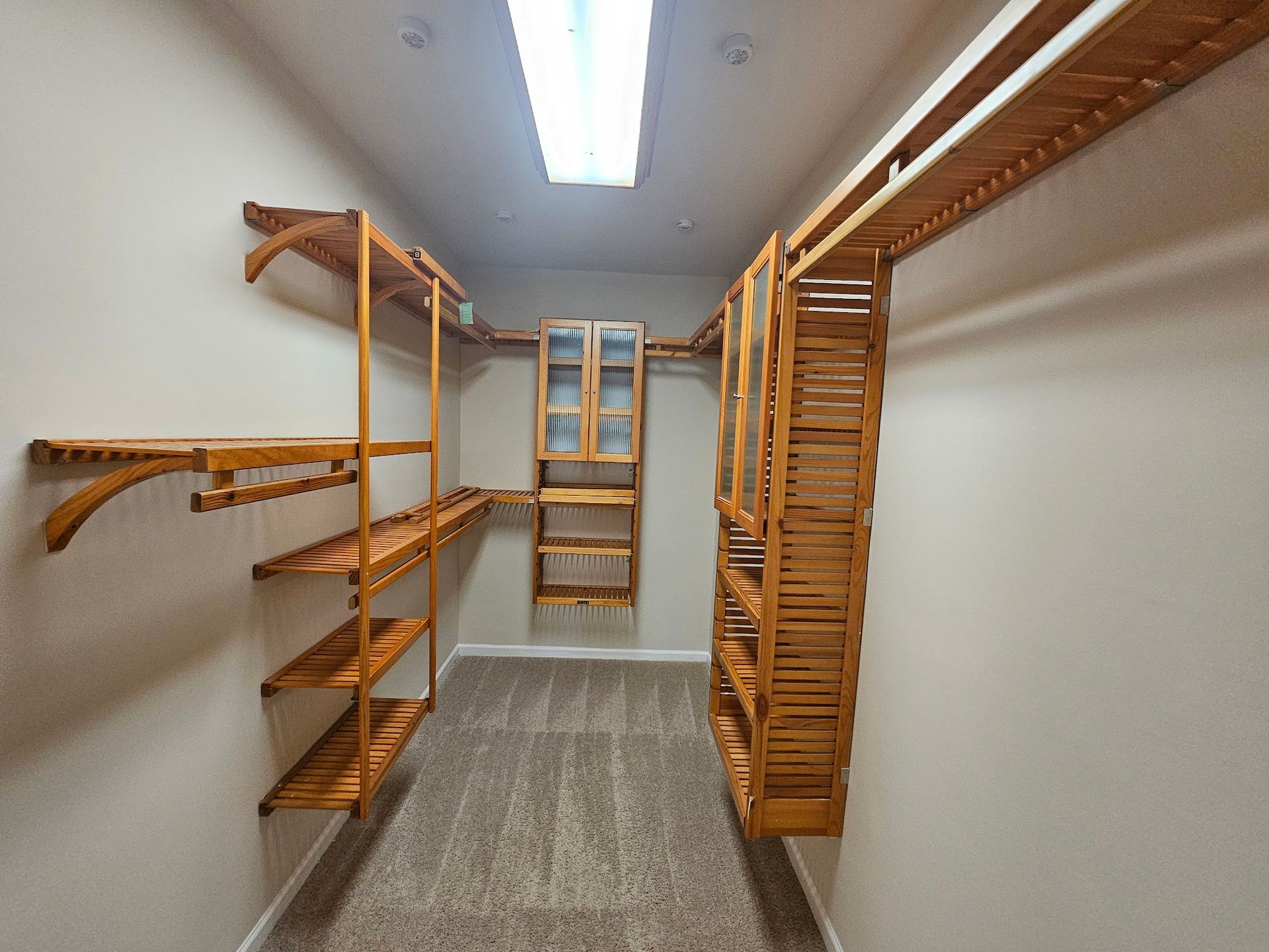 A walk in closet with wooden shelves and a window.